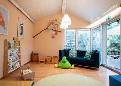 Der hintere Teil des Spielzimmers mit Sofa, links das Bücherregal, rechts der Zugang zur Terrasse.